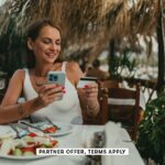 SOCIAL IMAGE PARTNER OFFERS TERMS APPLY Woman using a smartphone and paying with a credit card in a restaurant cream ph 25